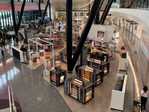 Modern airport duty-free shop with various products and shoppers.