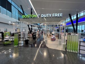 Interior of Boston Logan Airport with duty-free shops and modern design.