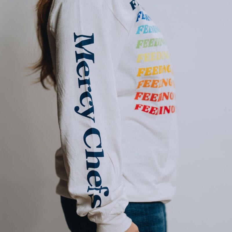 A side view of Mercy Chefs' white Feeding Body and Soul long sleeve