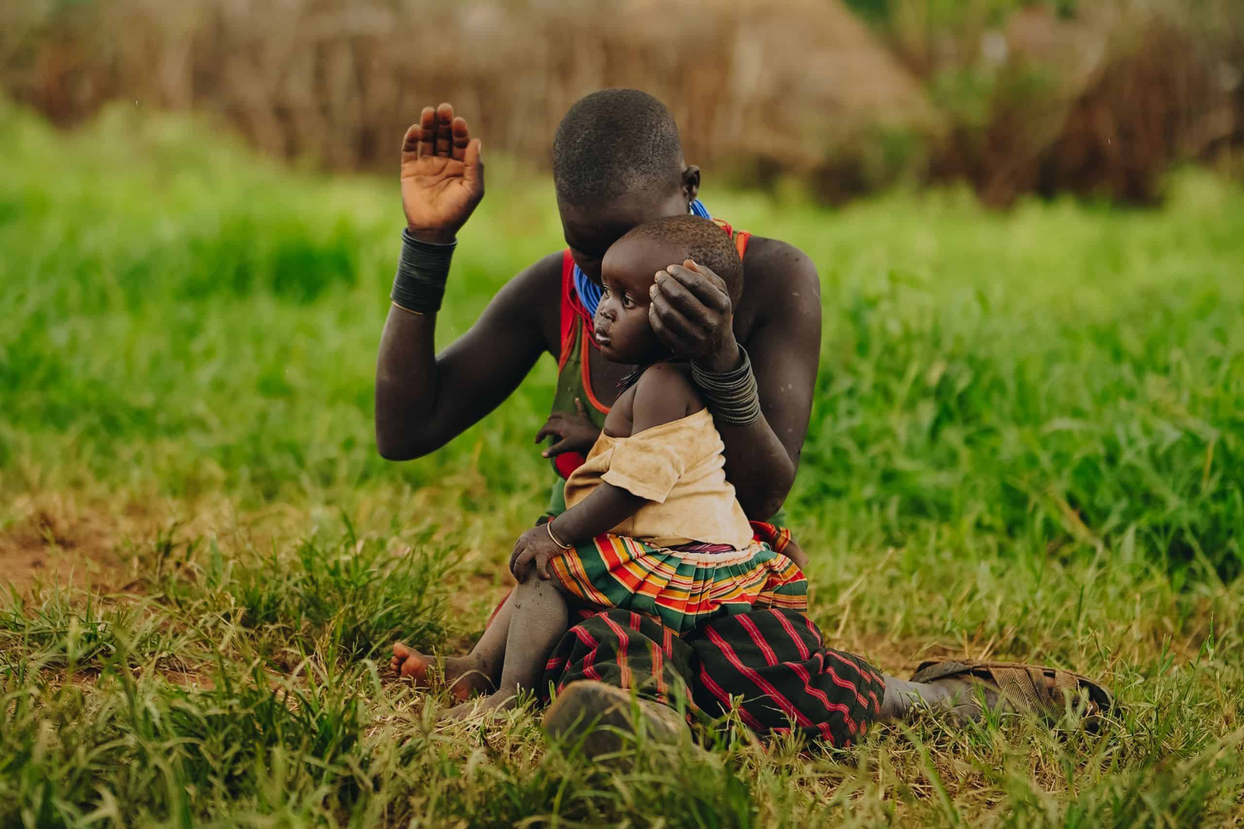 Ugandan mother praying while holding her child in her arms.