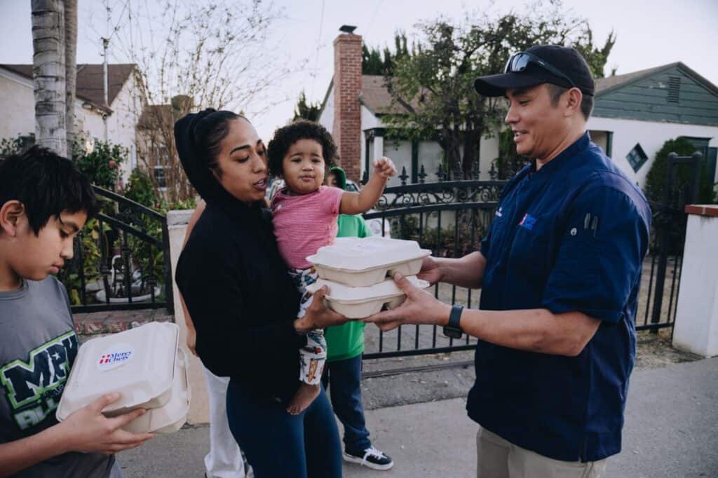 Chef Chris Caton hands a Mercy Chefs meal to Maria and her children in the aftermath of the California wildfires.