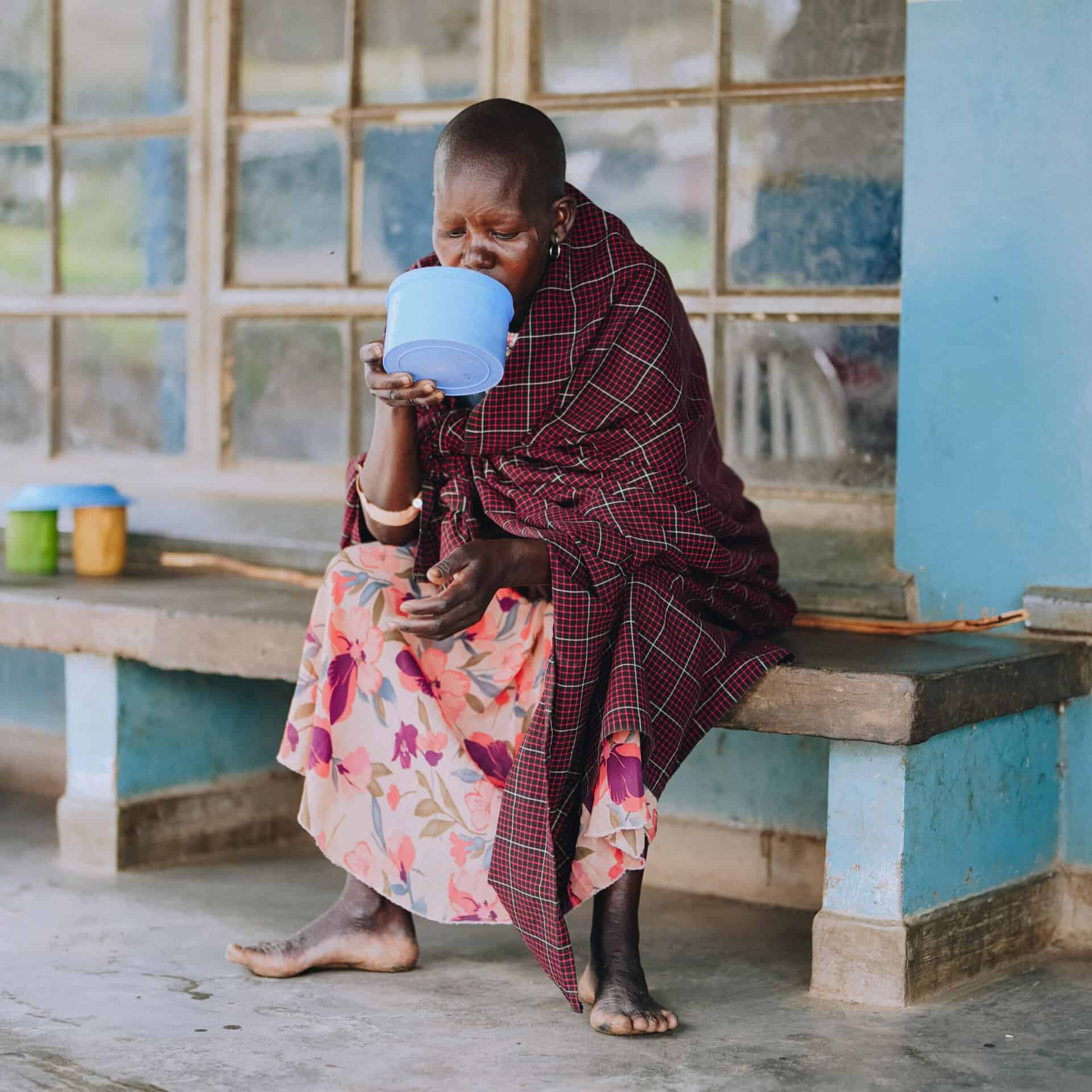 A woman drinks water in a Ugandan hospital