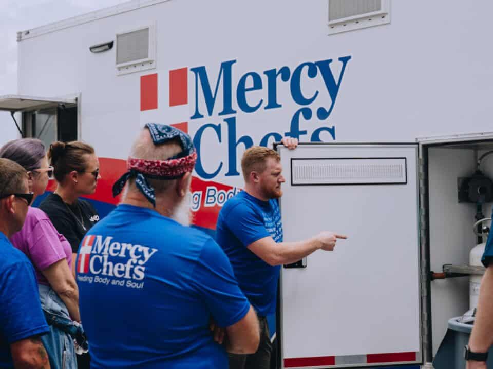 A Mercy Chefs staff member gives volunteers a mobile kitchen tour