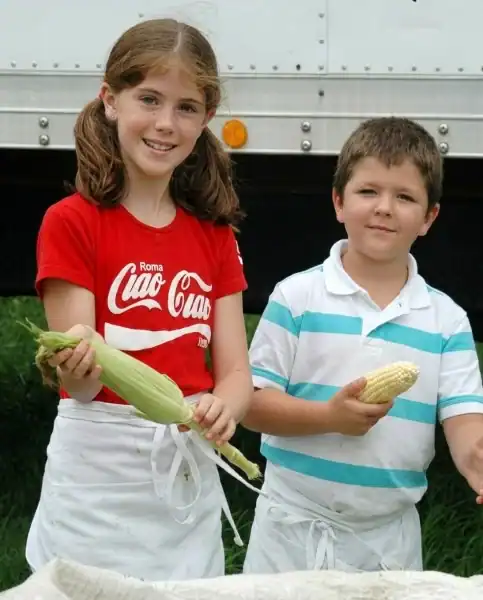 Young Megan and Raymond LeBlanc holding corn in Conklin, New York