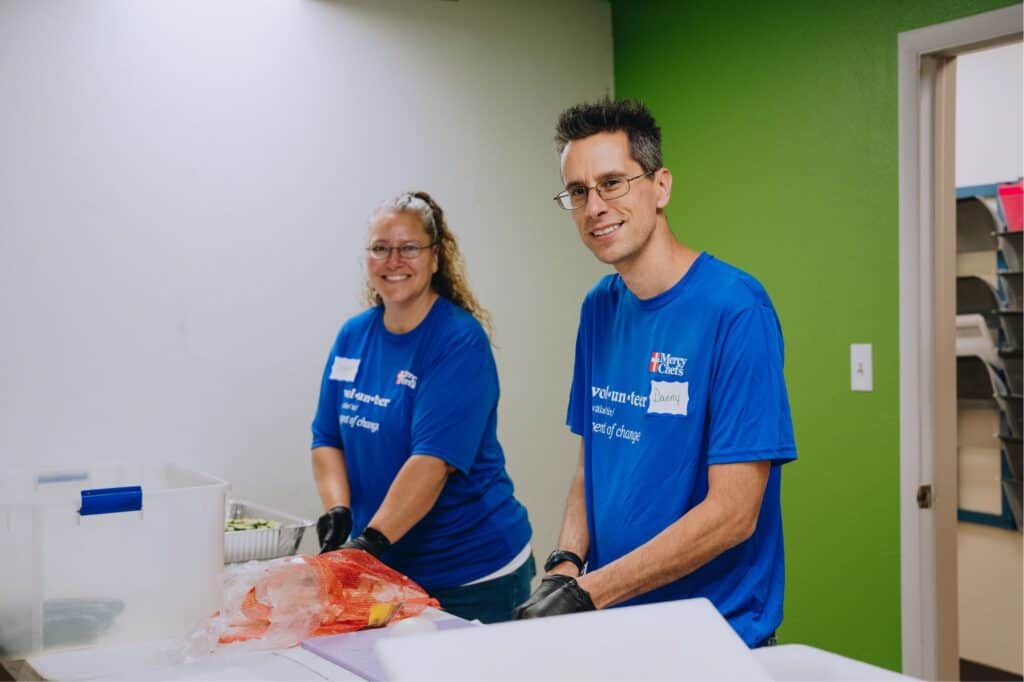 Two Mercy Chefs volunteers chop vegetables