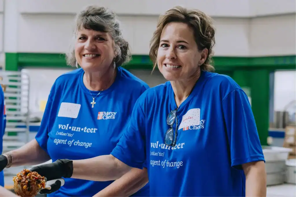Two volunteers in Washing smiling as the serve meals