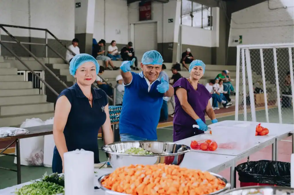Church volunteers smile and give thumbs up in as they prepare meals, Colombia