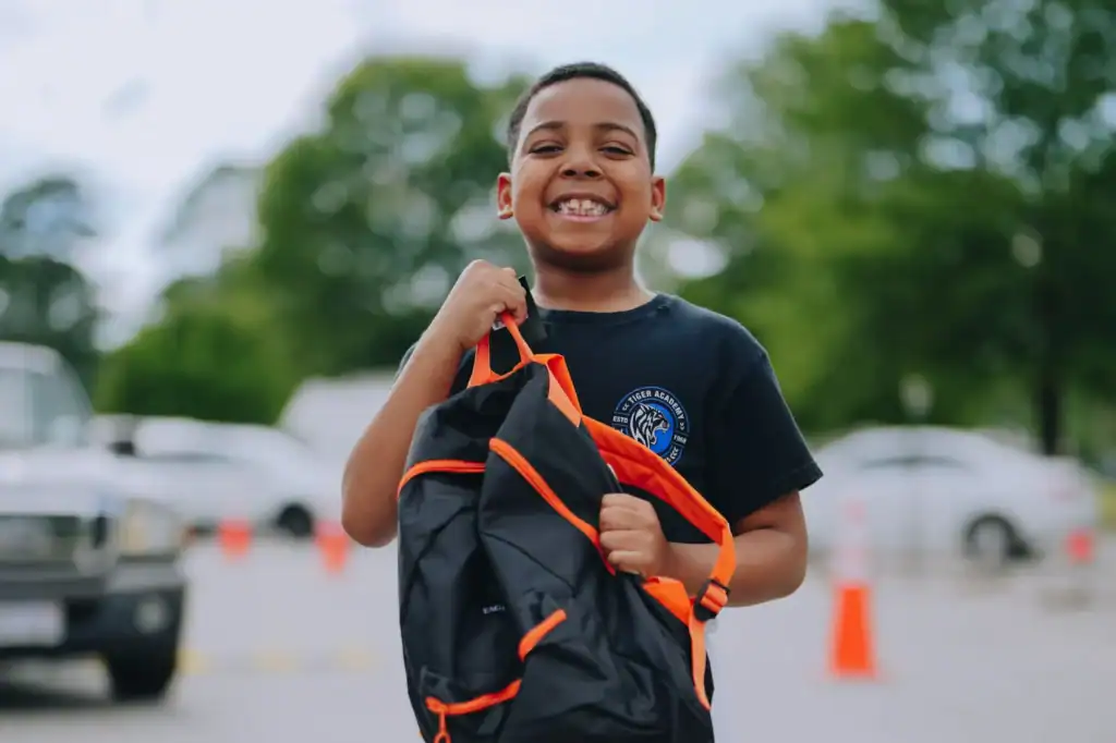 Boy smiles as he holds a new backpack in Portsmouth, Virginia