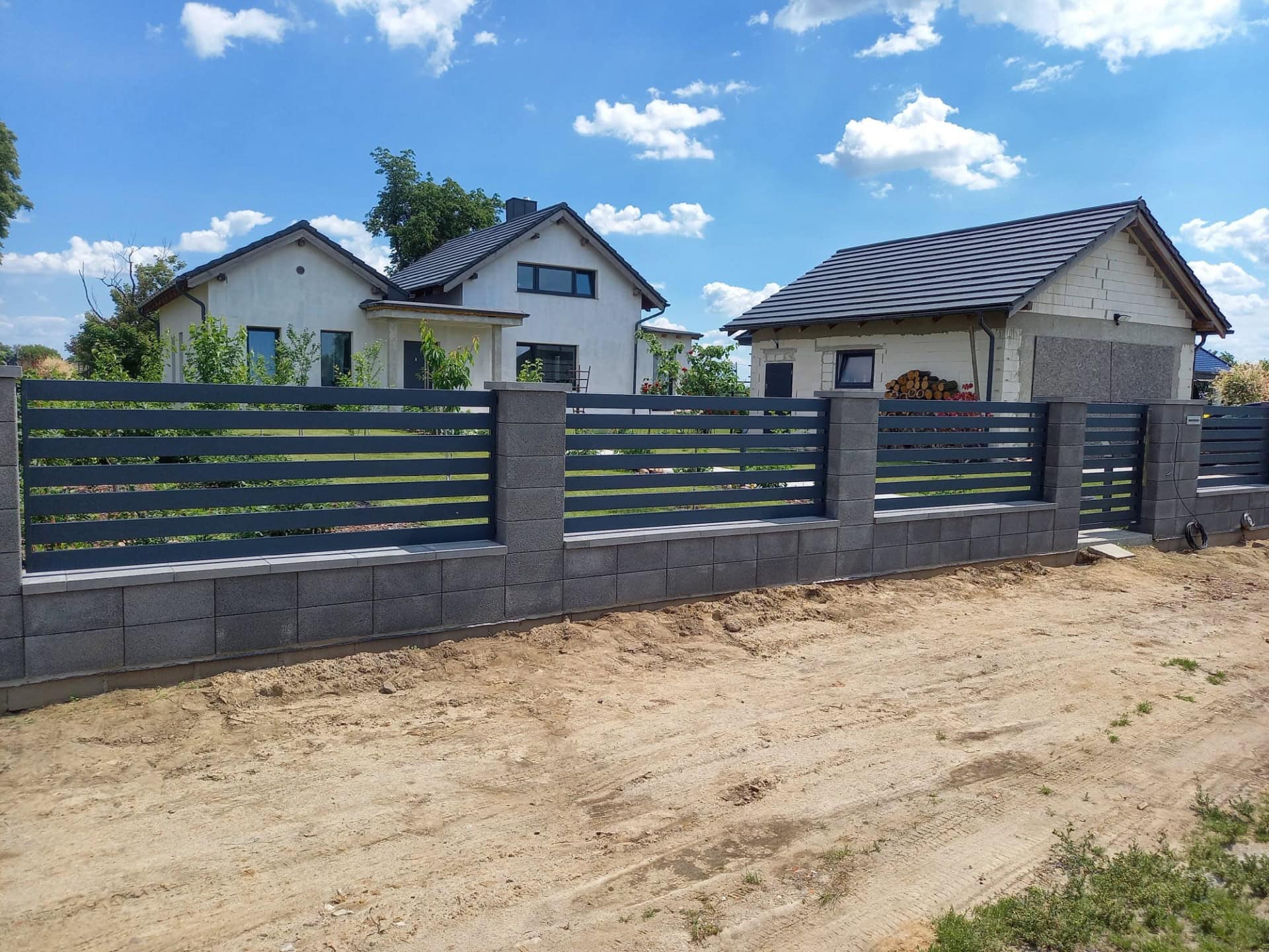 Szerokie, poziome panele ogrodzeniowe z metalu, czarne, na betonowej podstawie - ogrodzenie Metal-Serwis Obrzycko.