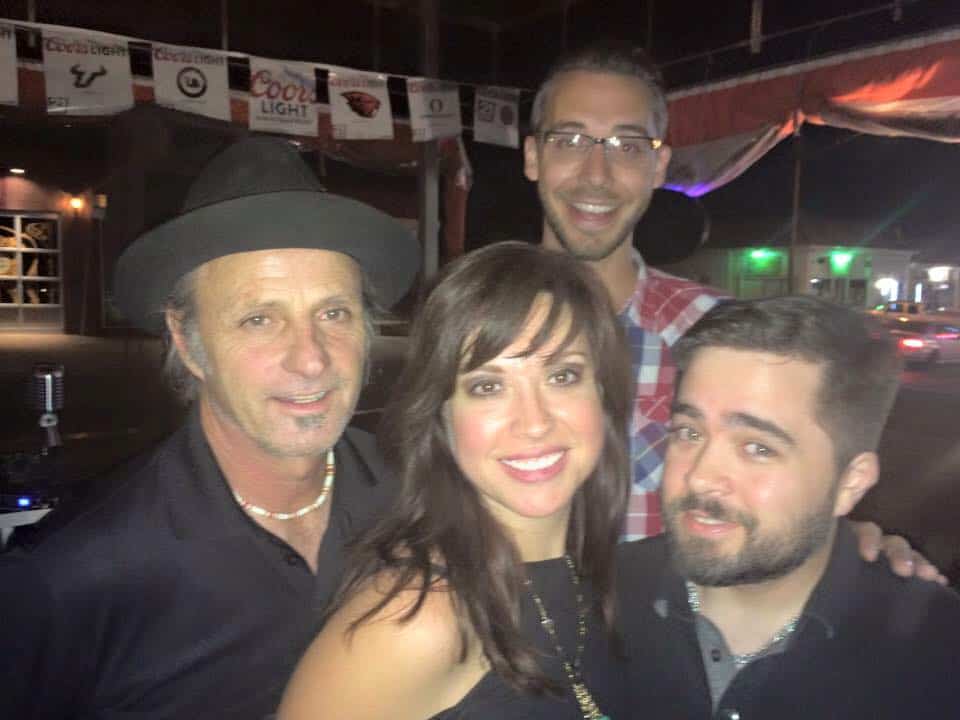 Group of four friends smiling at a weekend event under a tent.