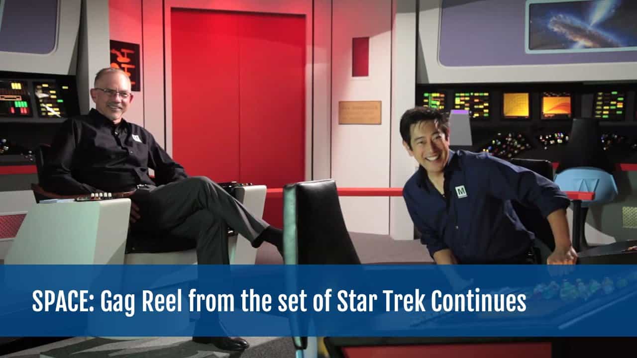 Two men on the set of Star Trek with control panels in the background.