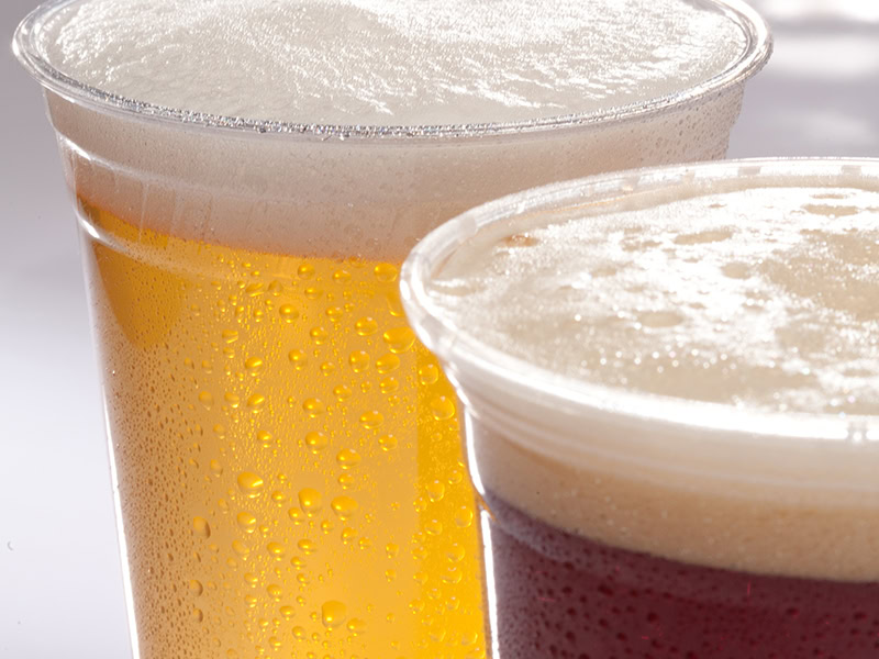 Two glasses of beer with frothy heads on a table.