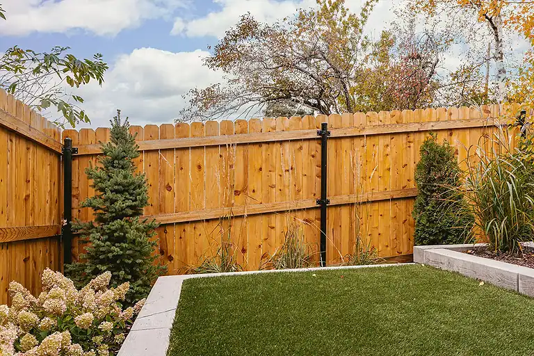 Fencing installation with wooden panels and decorative plants in a backyard.