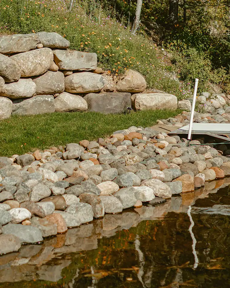 Decorative rocks lining shoreline with water reflection and natural landscape.