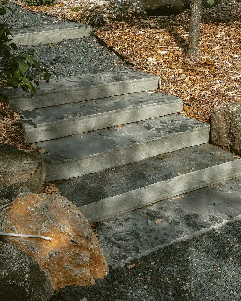 Stone staircase for shoreline access with natural landscaping and rocks.
