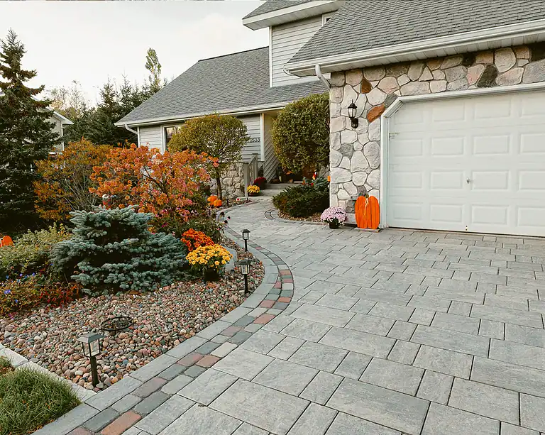 Beautiful stone pathway leading to a house with vibrant autumn foliage.