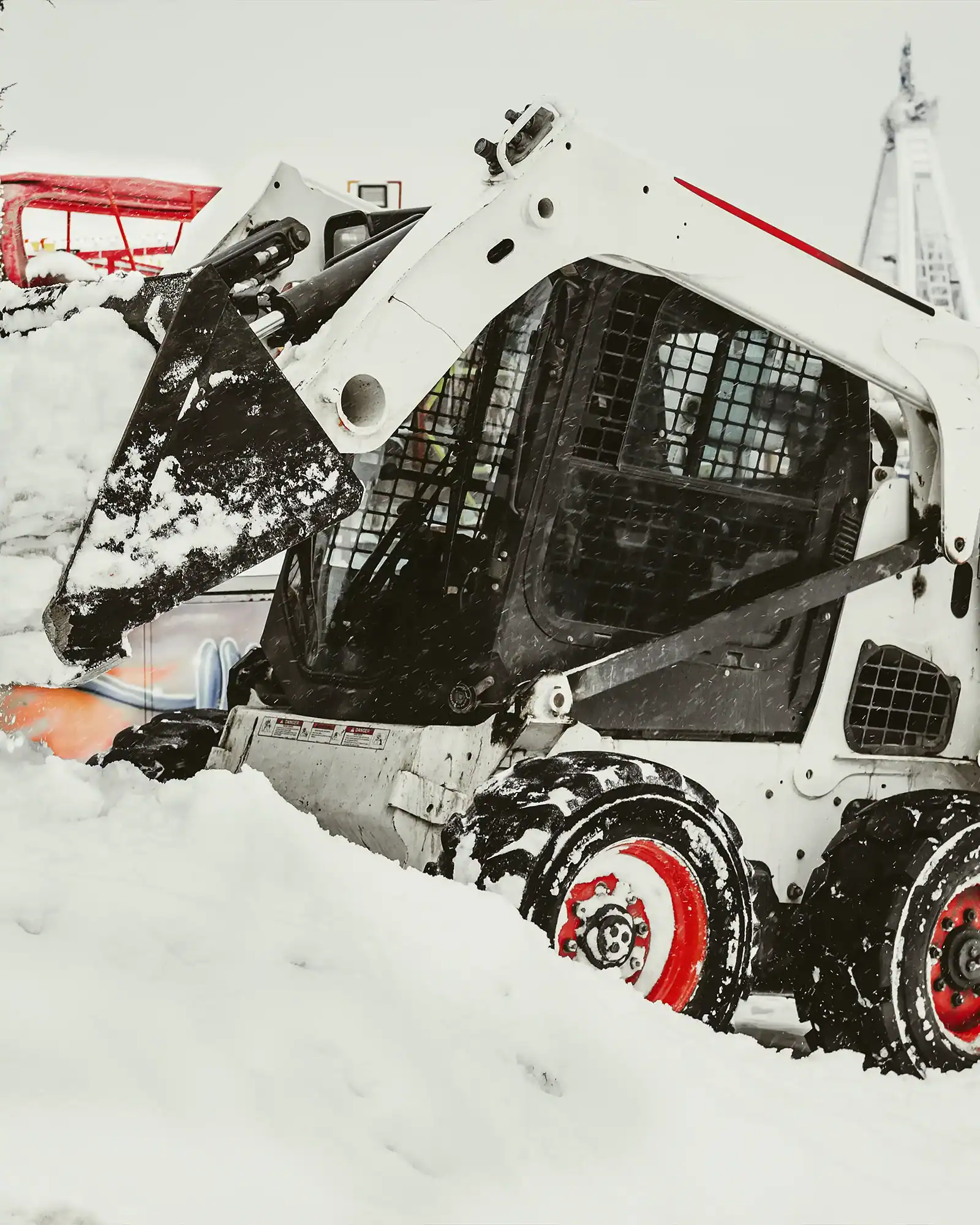 Snow removal with skid-steer loader in winter landscape.