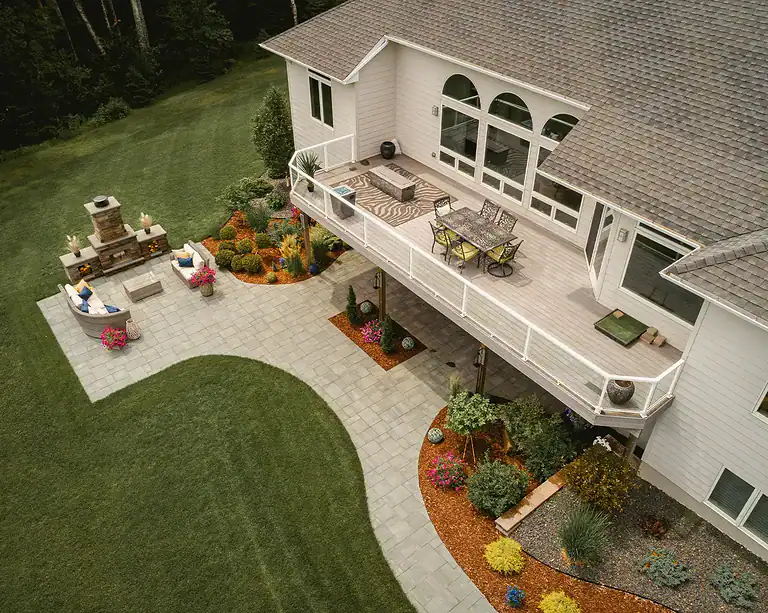 Beautiful backyard oasis featuring a spacious deck, lush lawn, and vibrant flower beds. Perfect for.