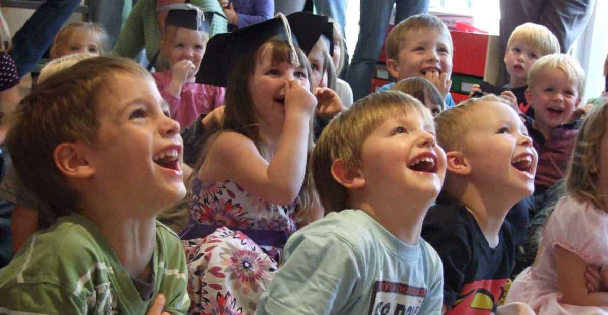 A group of children are laughing while sitting on the floor.