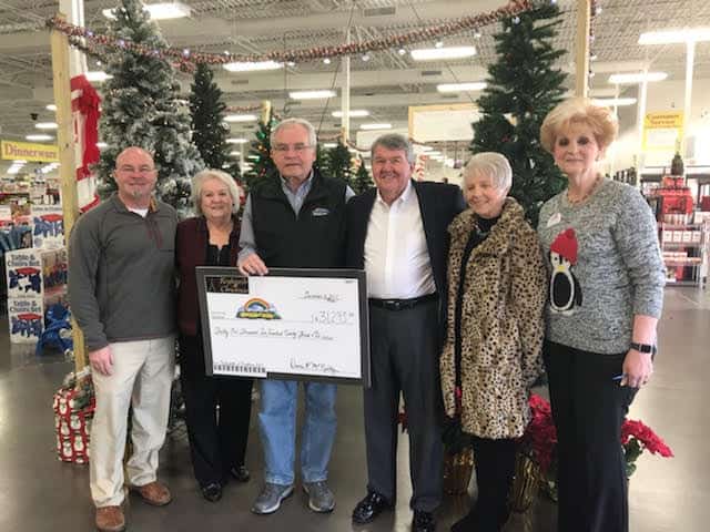 A group of people standing in front of a christmas tree in a store.