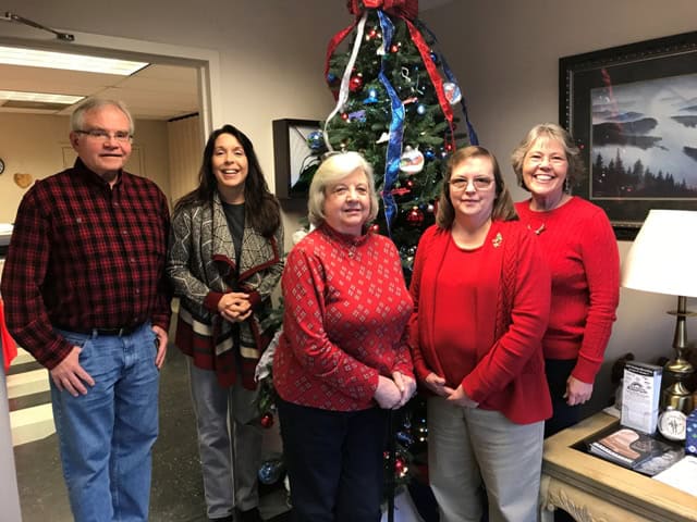 A group of people standing in front of a christmas tree.
