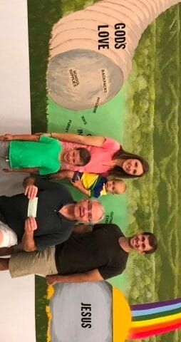 A group of people posing in front of a mural.