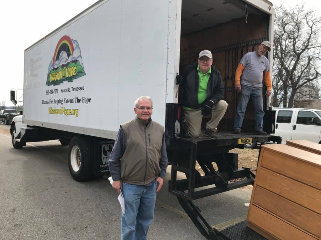 Three men standing in front of a moving truck.