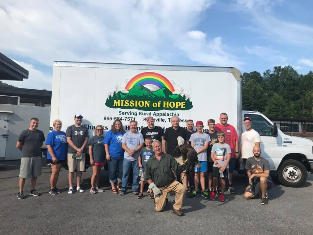 A group of people posing in front of a truck.