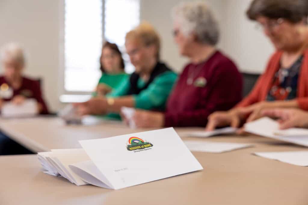 A group of elderly women are sitting around a table.