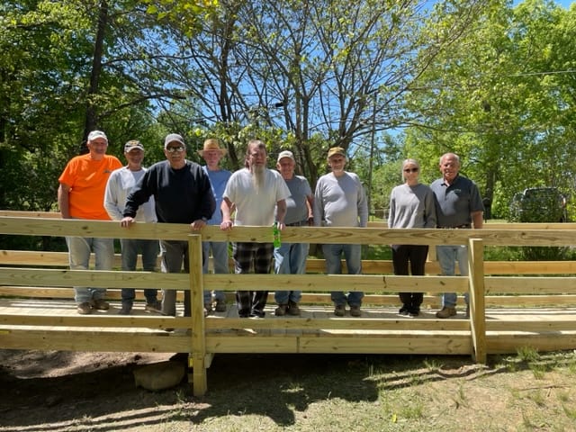 A group of men standing on a wooden bridge.