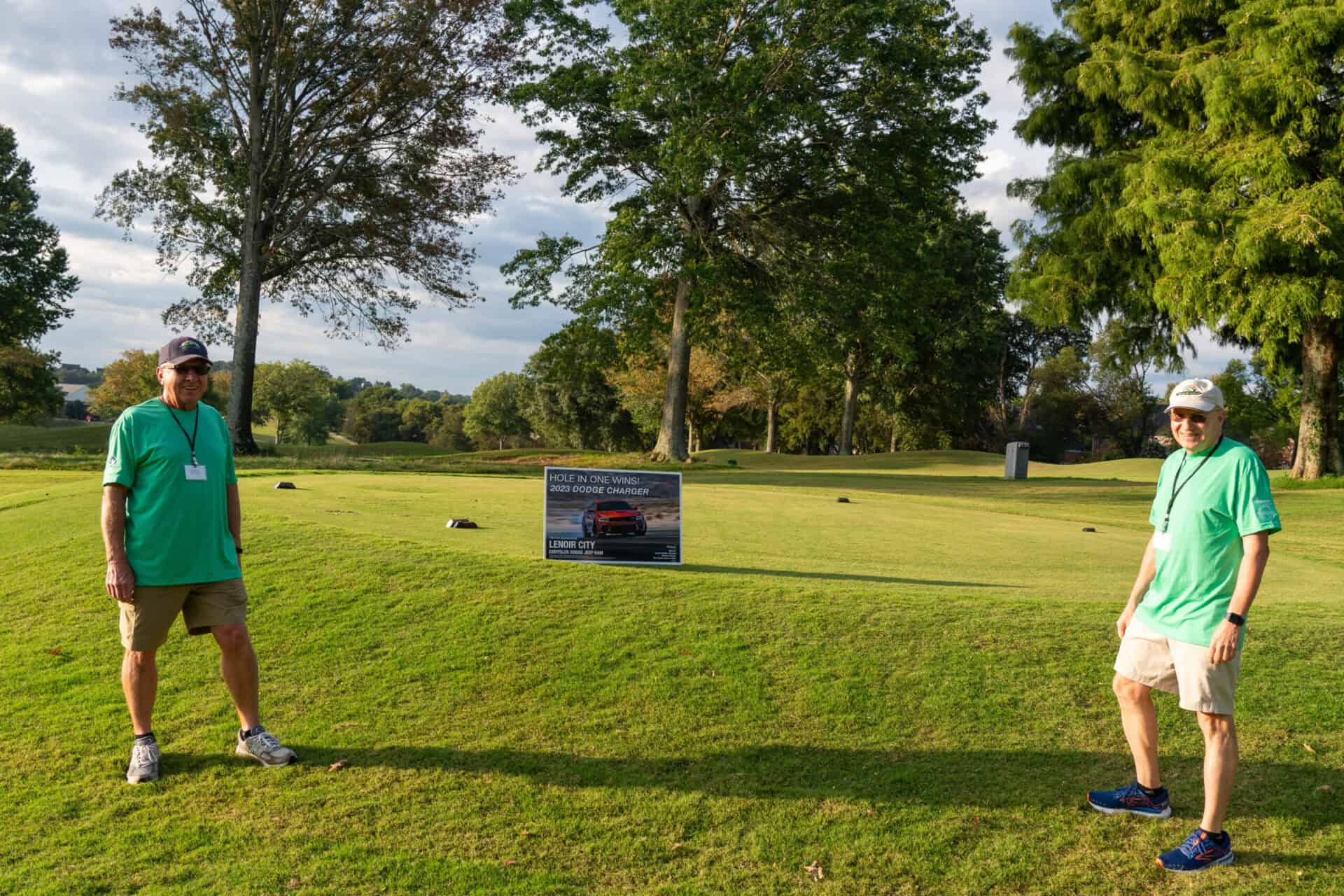 Two men standing on a green golf course.
