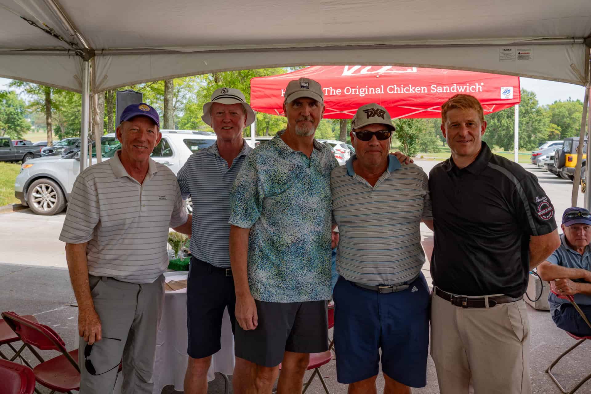A group of men posing for a picture under a tent.