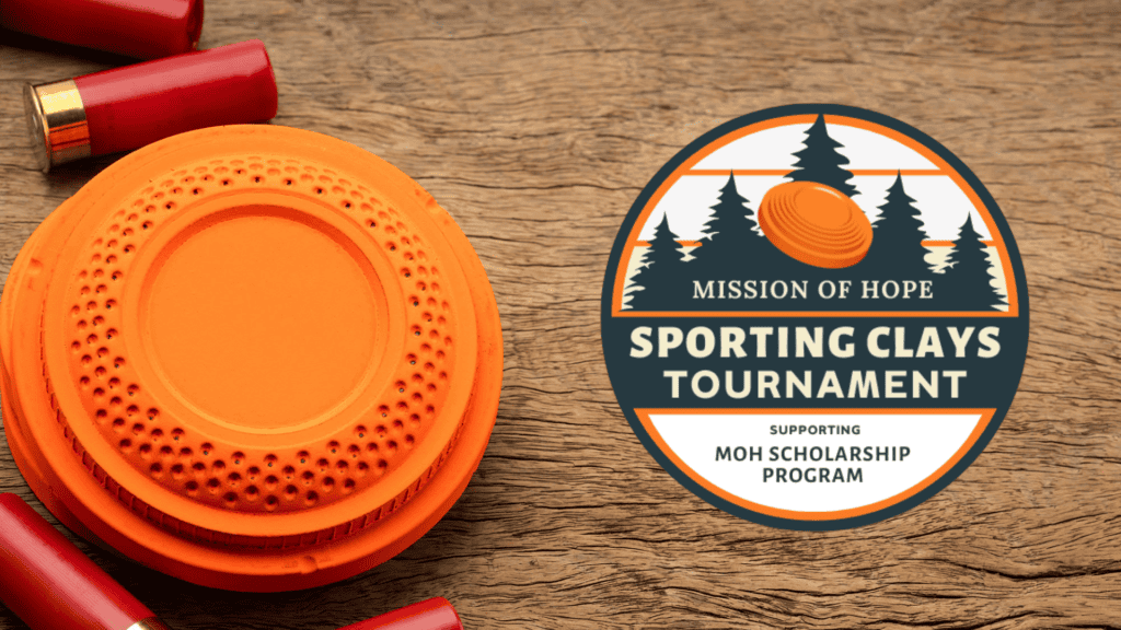 Clay pigeon and shotgun shells displayed with a "mission of hope sporting clays tournament" badge on a wooden surface.