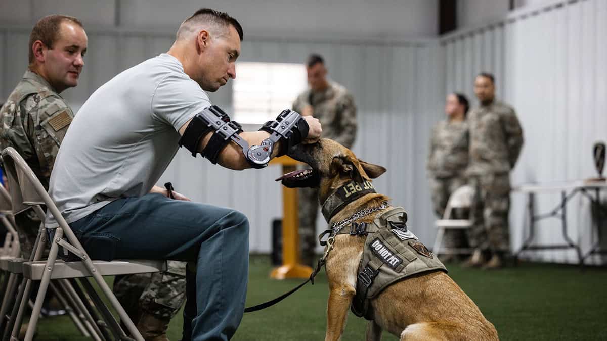 Master Sgt. Adam Macowicz comforts Military Working Dog Rita during her retirement ceremony hosted by the 412th Security Forces Squadron at Edwards Air Force Base, California, Sept. 25. Rita and MWD Llouisiana officially retired after years of service protecting base personnel, visiting dignitaries and critical defense assets.
