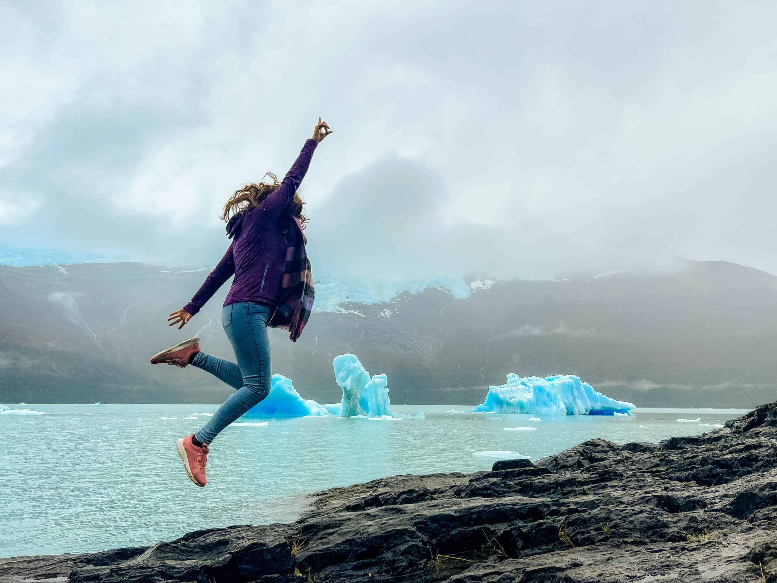 Turista saltando frente a un iceberg en El Calafate
