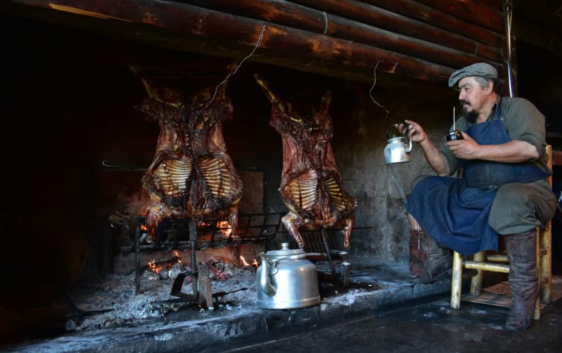Gaúcho preparando cordeiro assado e mate no fogo na Estancia Nibepo Aike