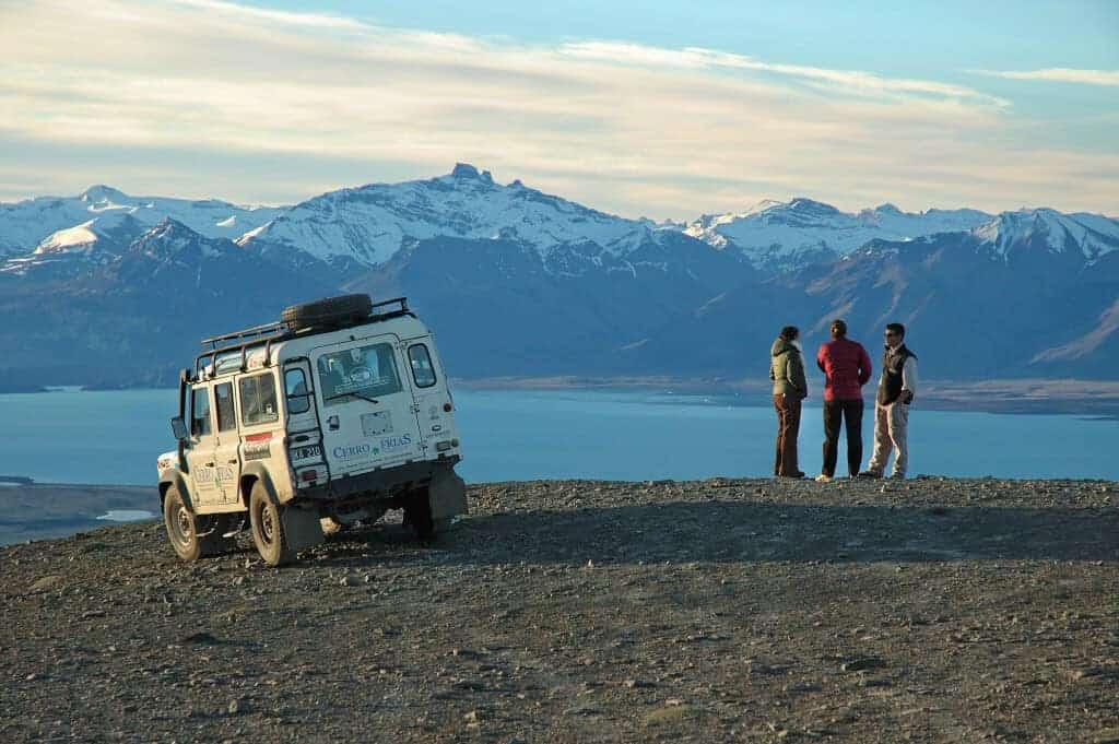 Viajantes junto ao veículo de safári do Cerro Frías com montanhas nevadas ao fundo