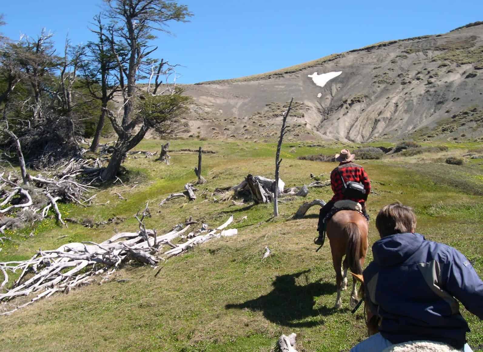 Cavaleiros descendo a cavalo pela várzea patagônica no Cerro Frías