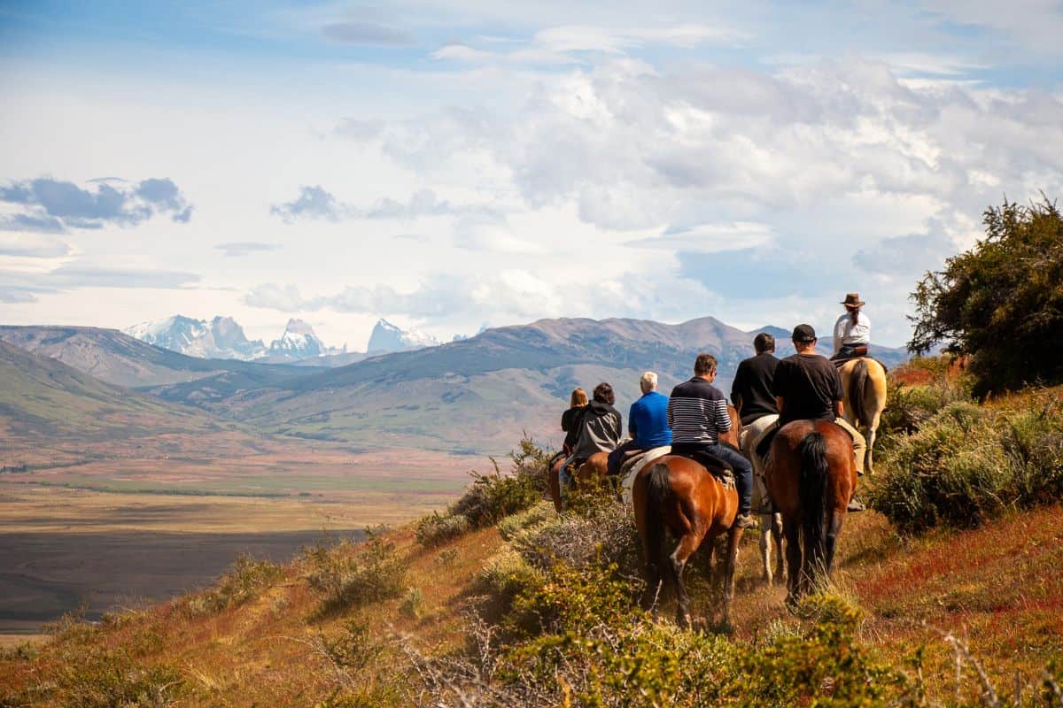Grupo a cavalo na encosta do Cerro Frías com montanhas ao fundo