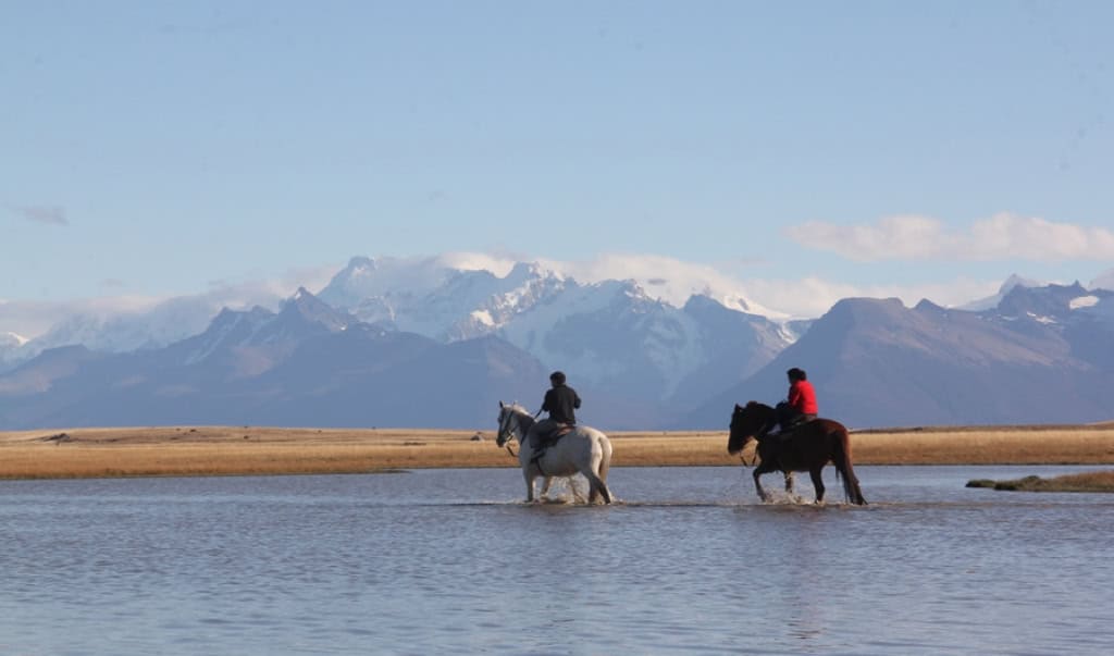 Cavaleiros a cavalo na margem do Lago Argentino no Cerro Frías