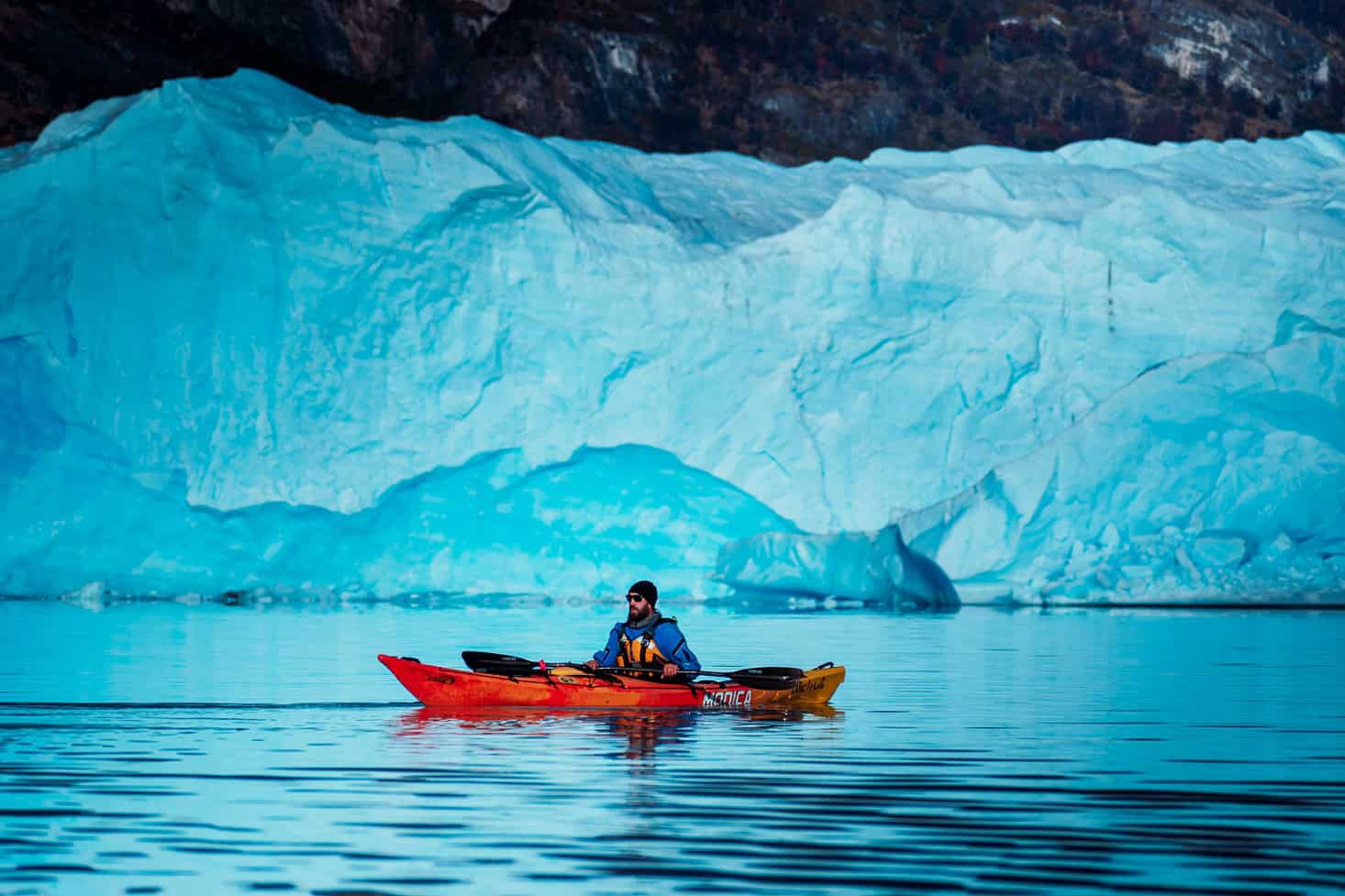 Caiaquista ao lado de um iceberg azul no Lago Argentino, Perito Moreno