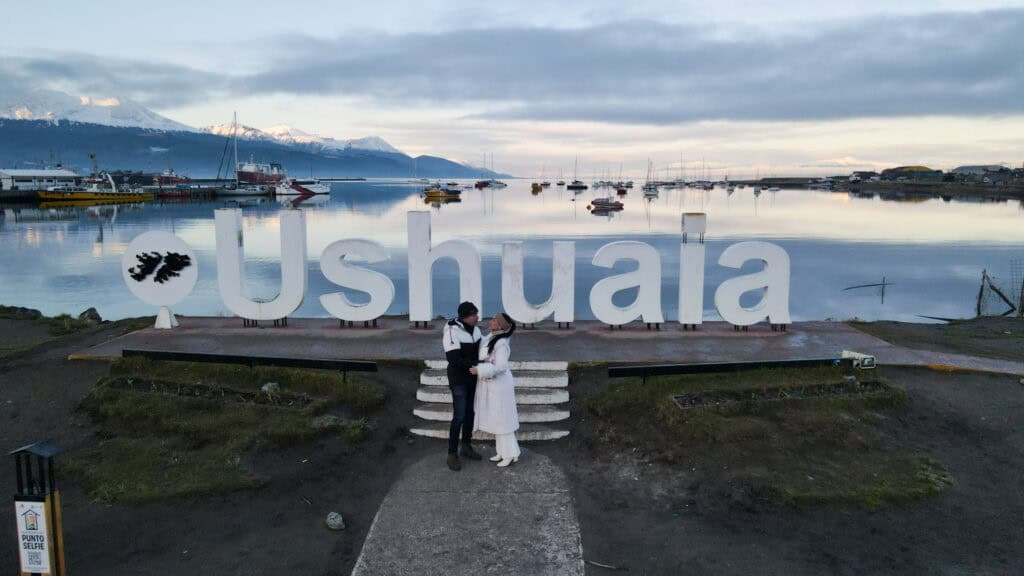 Placa de Ushuaia Fim do Mundo ao entardecer com o porto ao fundo