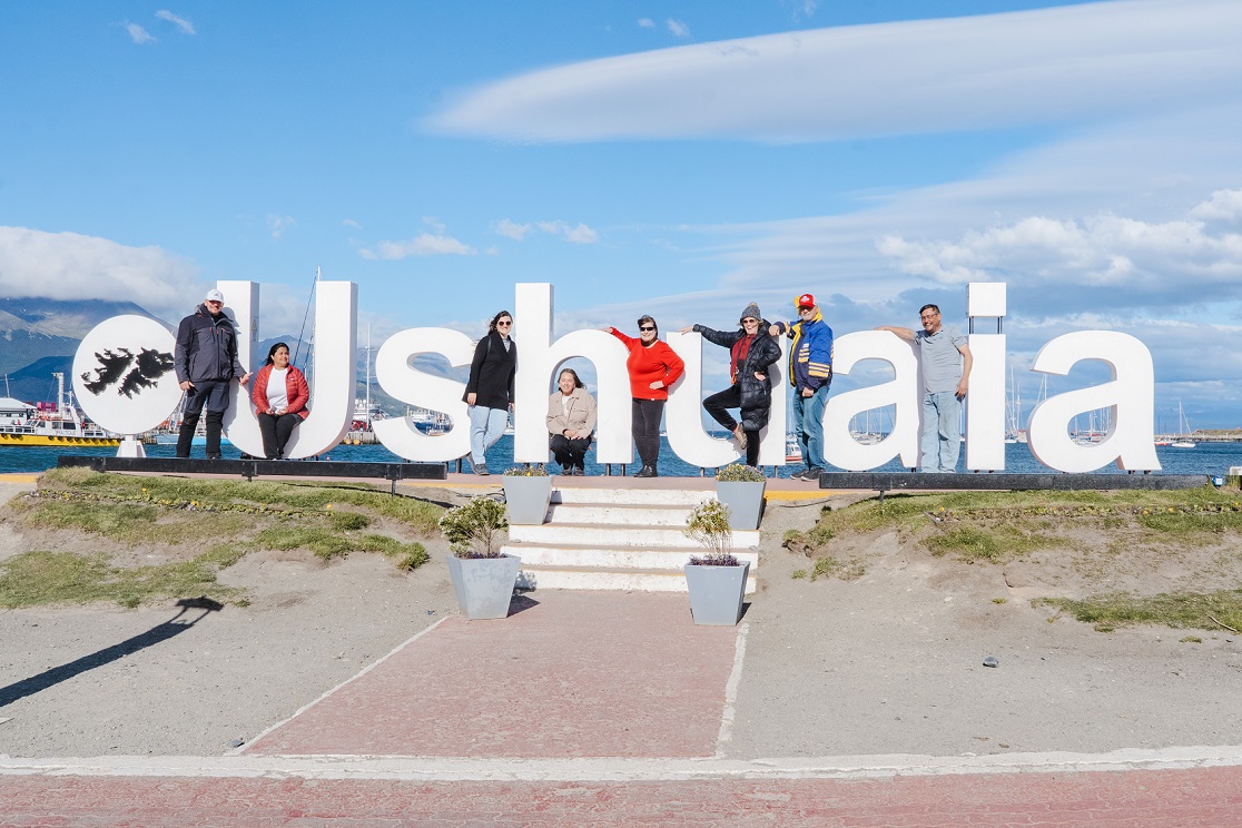 Grupo do City Tour City & Wine posando na placa de Ushuaia Fim do Mundo