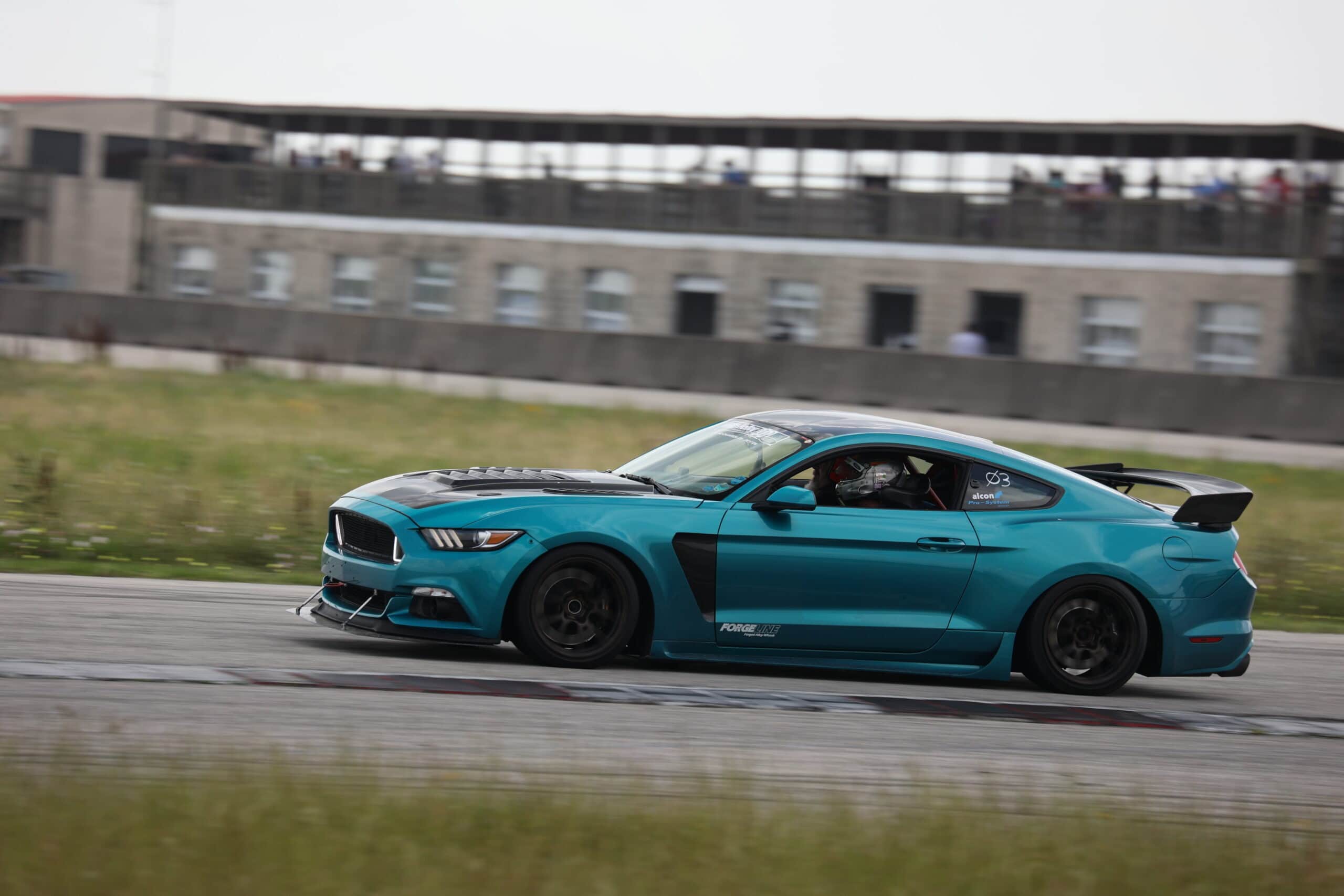 Blue Ford Mustang race car on track at Mustang Week event in Texas 2025.