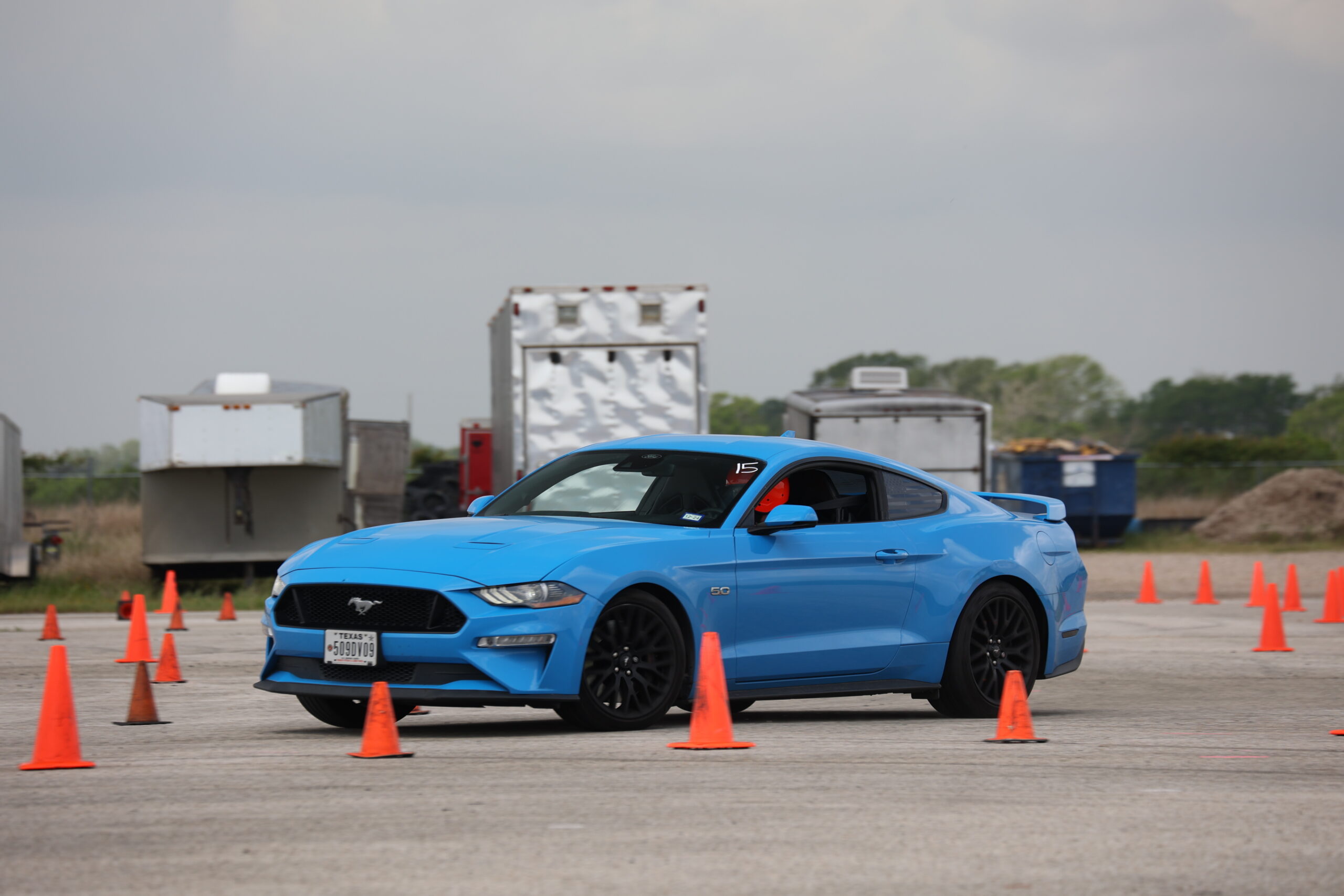 Blue Ford Mustang driving through a cone course at Mustang Week event.