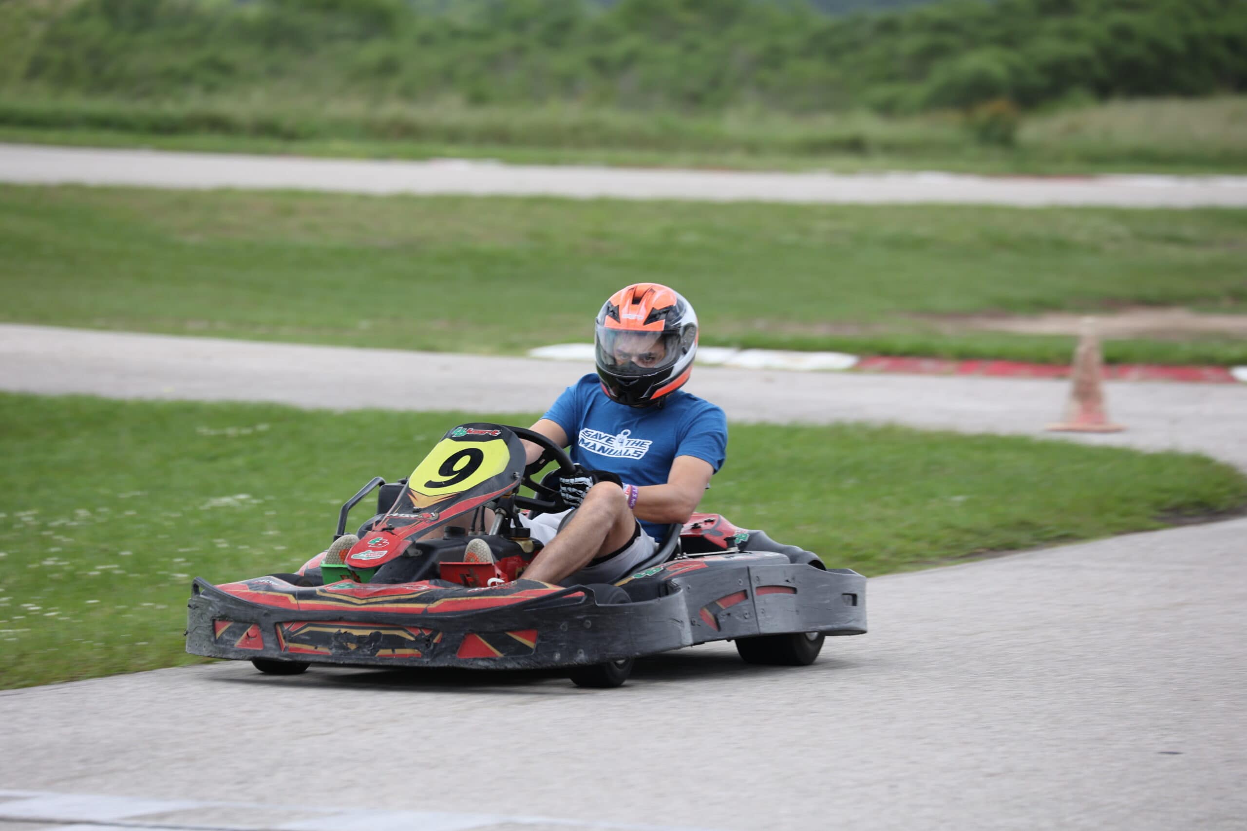 Young person racing a go-kart on a track during Mustang Week event.