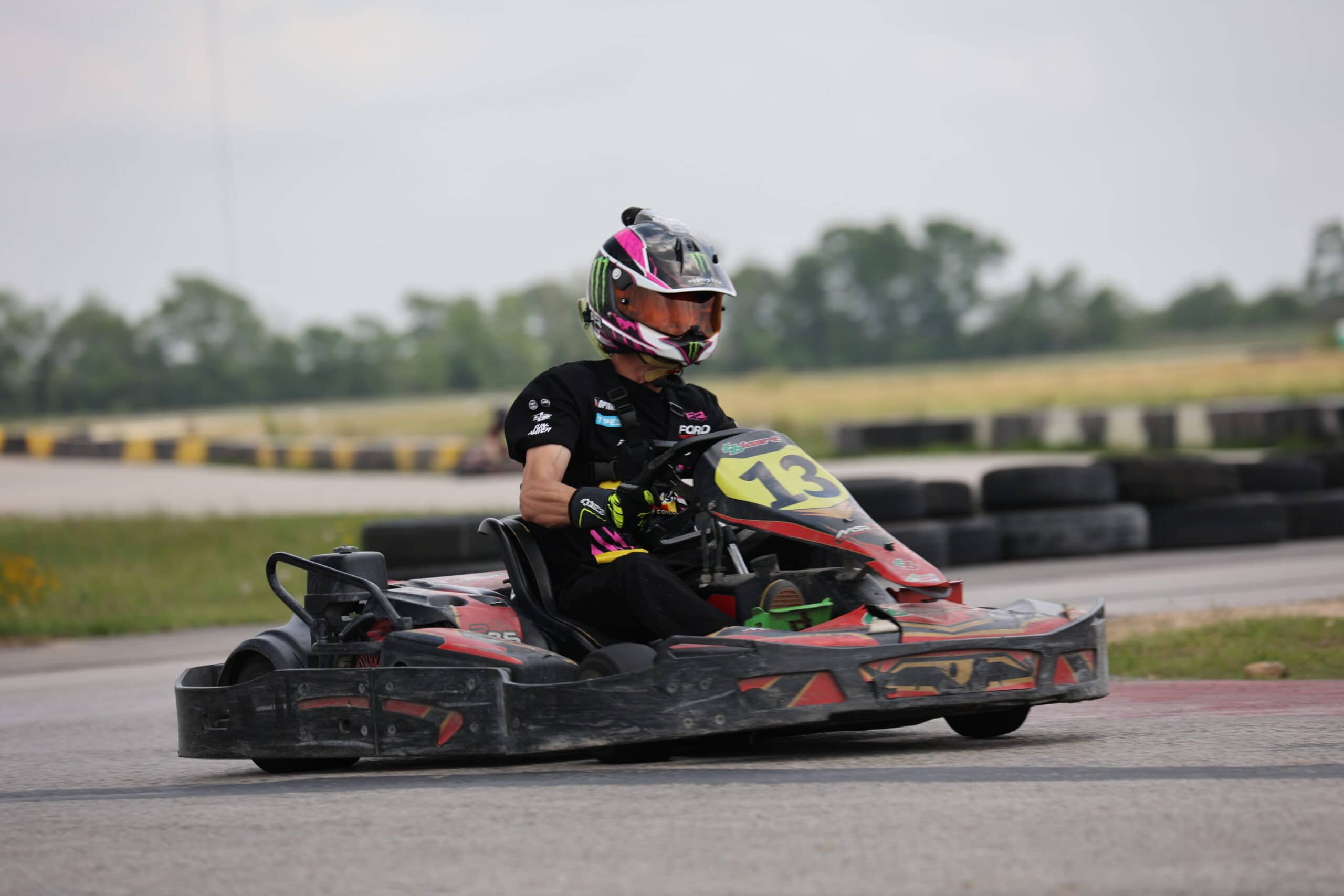 Young go-kart racer wearing helmet and racing suit on track at Mustang Week.