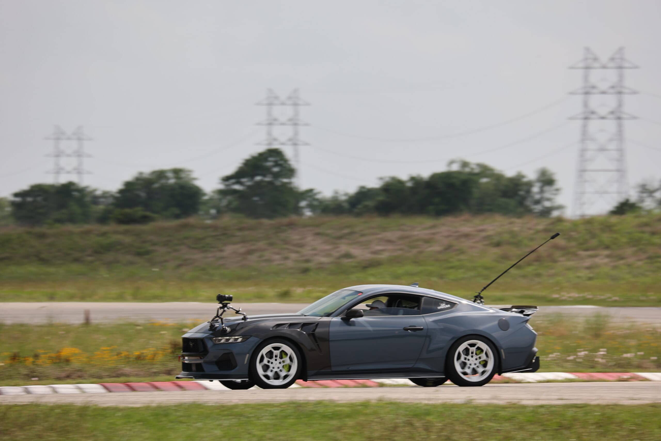Dark gray sports car racing on track during Mustang Week event in Texas 2025.