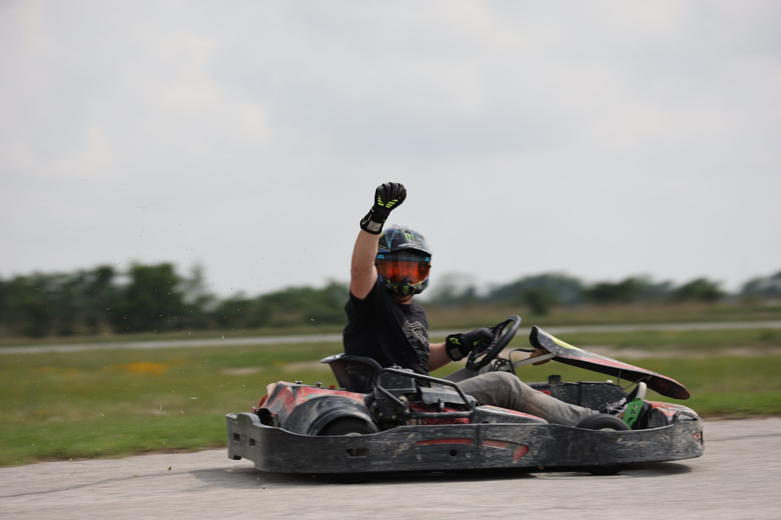 Person in go-kart wearing helmet and gloves at Mustang Week event.