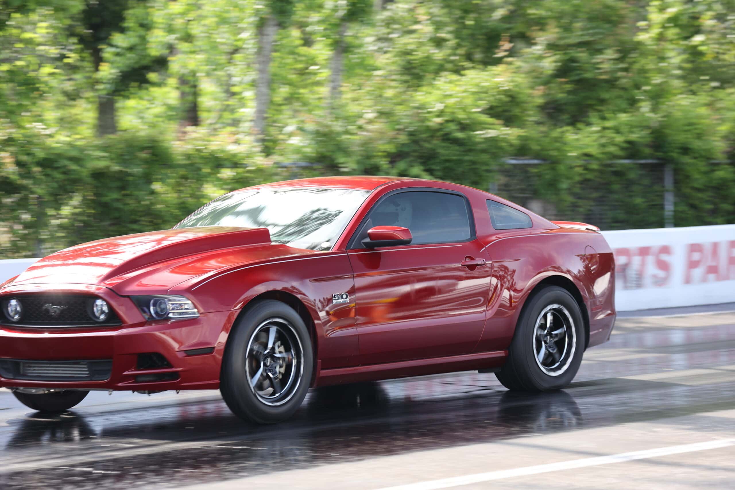 Red Ford Mustang racing on a drag strip during Mustang Week.